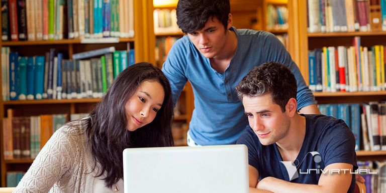 Tres estudiantes universitarios trabajando juntos frente a un computador portatil en una biblioteca